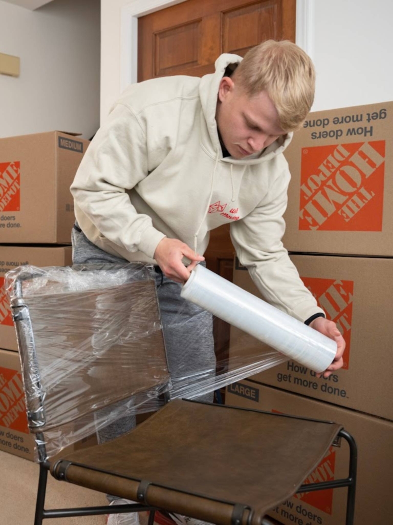 Wolf Moving of Raleigh team member wrapping a chair to protect it during the moving process