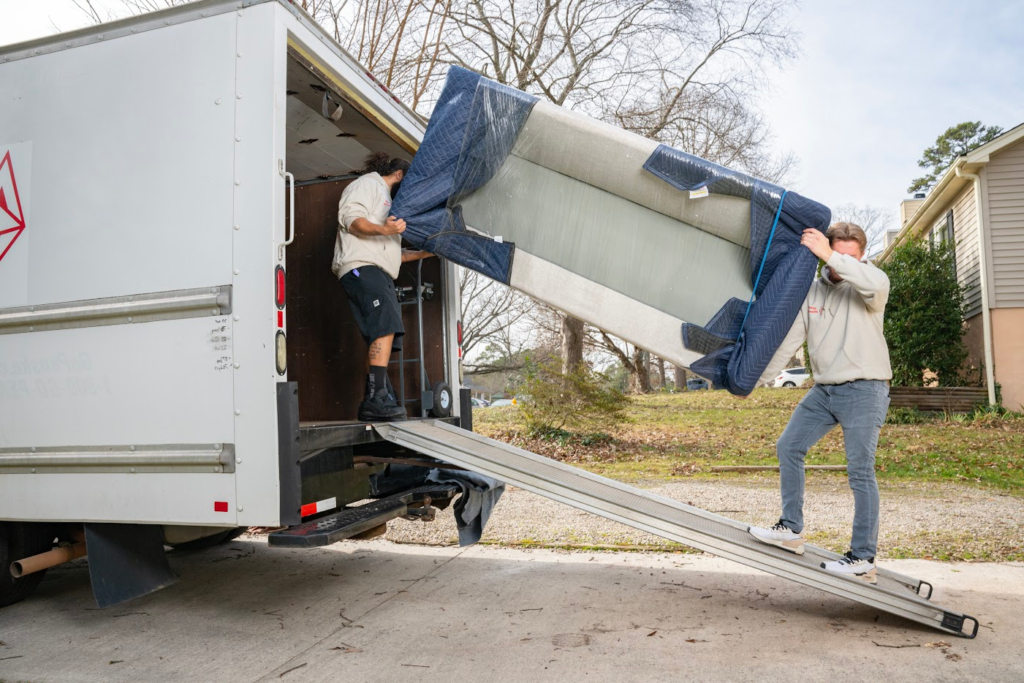 tw wolf moving employees loading a couch on to the back of a moving truck.