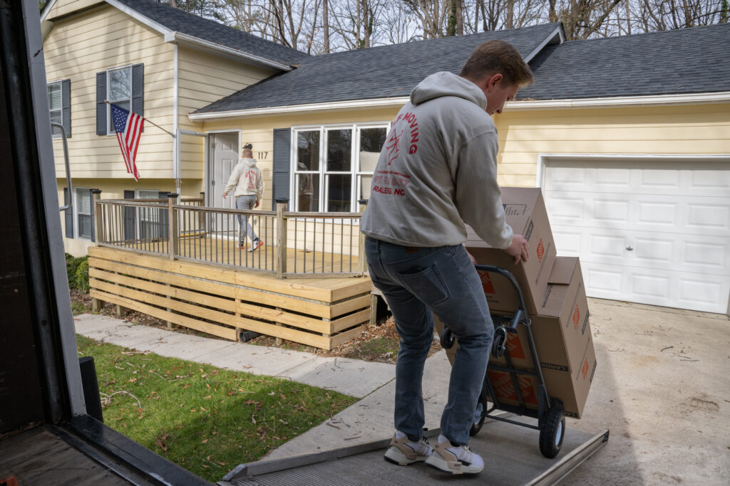 wolf moving employee pulling boxes up the ramp of a moving truck using a hand truck