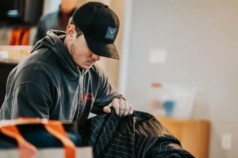 The owner of Wolf Moving covering a piece of furniture with a moving blanket.